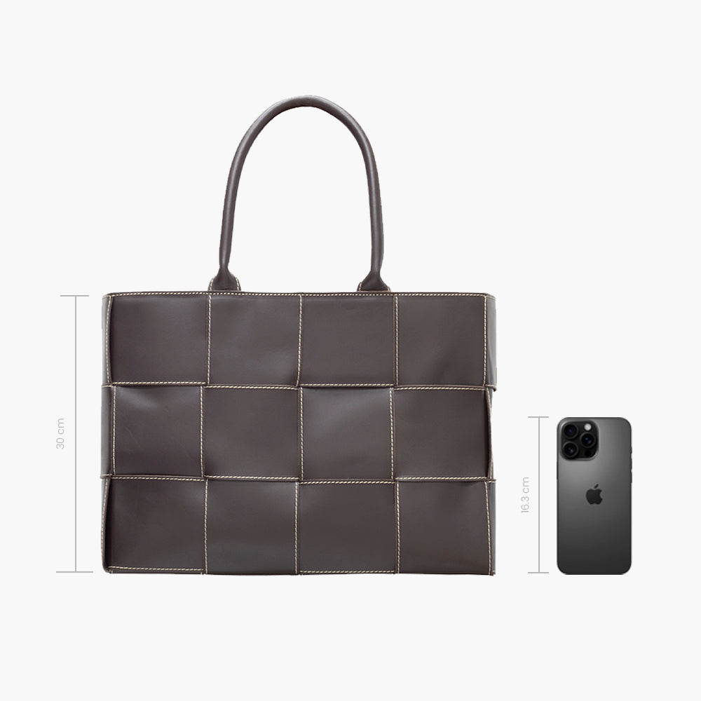 Bolsa tote café acolchada con diseño de paneles cuadrados y costuras blancas en contraste, asas dobles superiores y estructura amplia rectangular.