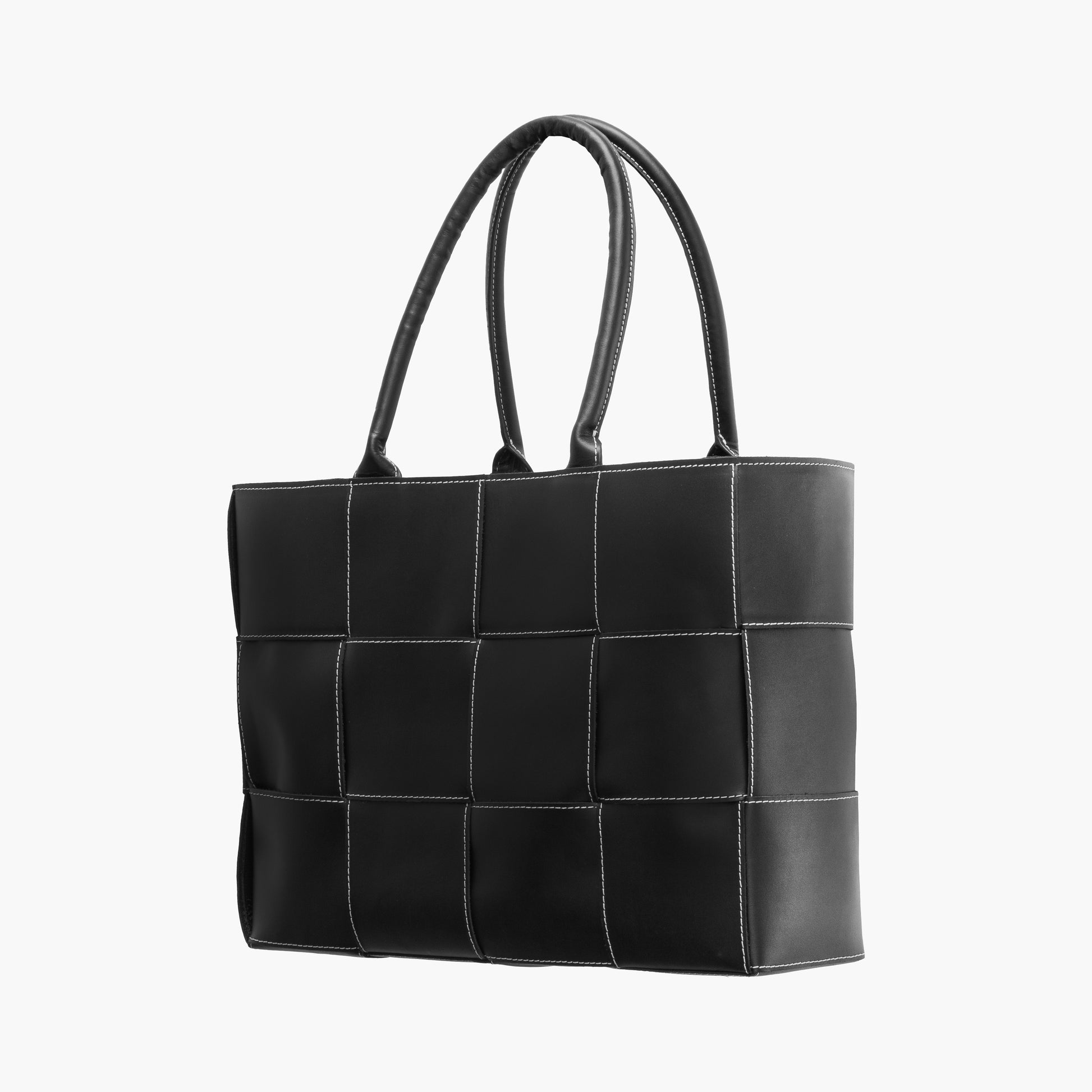 Bolsa tote negra acolchada con diseño de paneles cuadrados y costuras blancas en contraste, asas dobles superiores y estructura amplia rectangular.