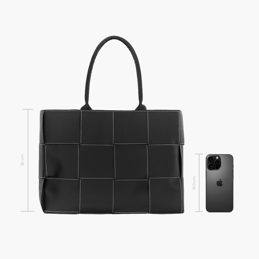 Bolsa tote negra acolchada con diseño de paneles cuadrados y costuras blancas en contraste, asas dobles superiores y estructura amplia rectangular.