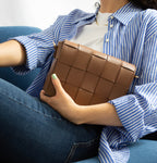 Bolso Thupe camel tejido en bloques estilo clutch con herrajes dorados en look casual elegante.