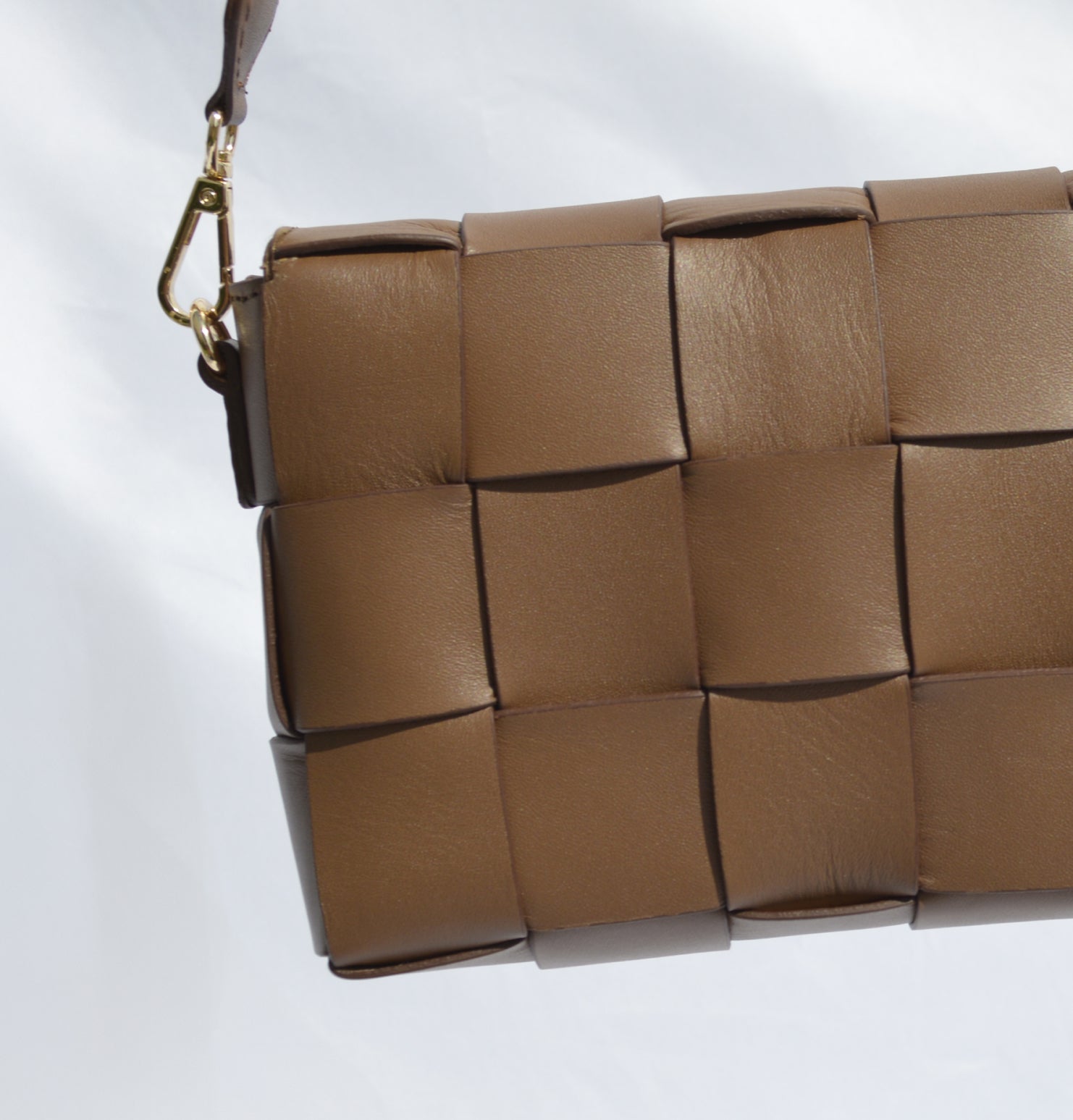 Detalle de bolso Thupe color camel con diseño tejido en bloques y herraje dorado lateral.